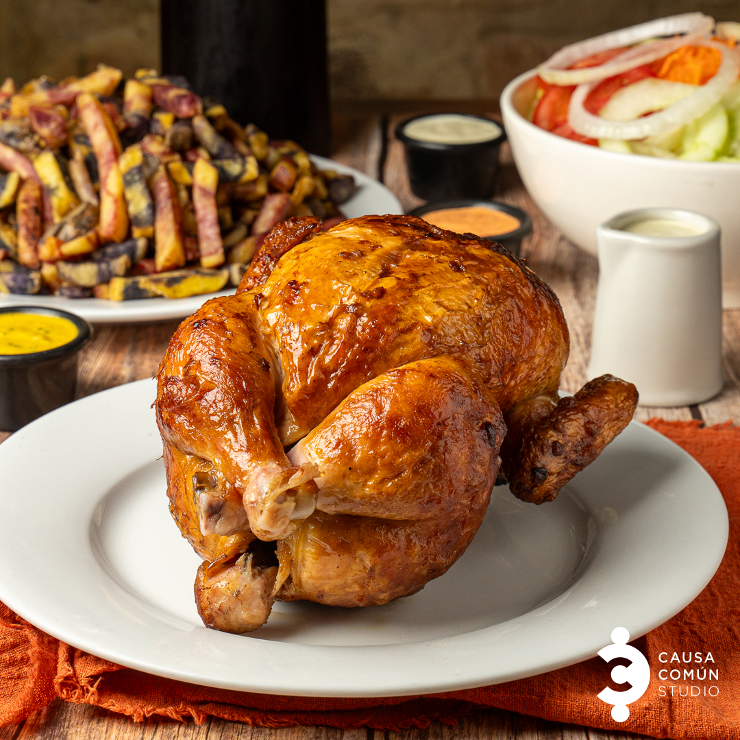 Pollo entero a la brasa presentado con ensalada, papas y salsas